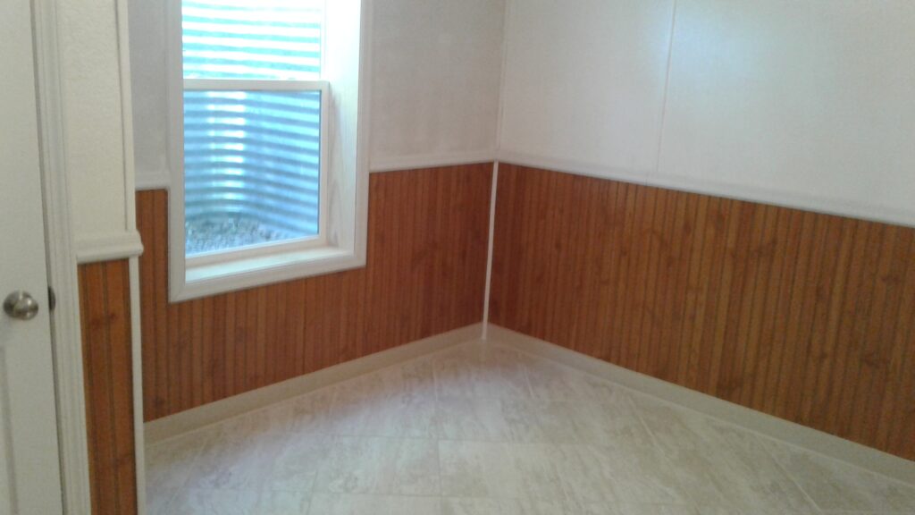 Custom basement bedroom renovation with heated tile flooring and wainscot style trim in Canton, SD.